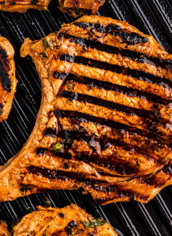 Grilled marinated pork chops on grill grates.