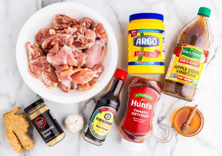 Ingredients for slow cooker honey garlic chicken on a white marble surface.