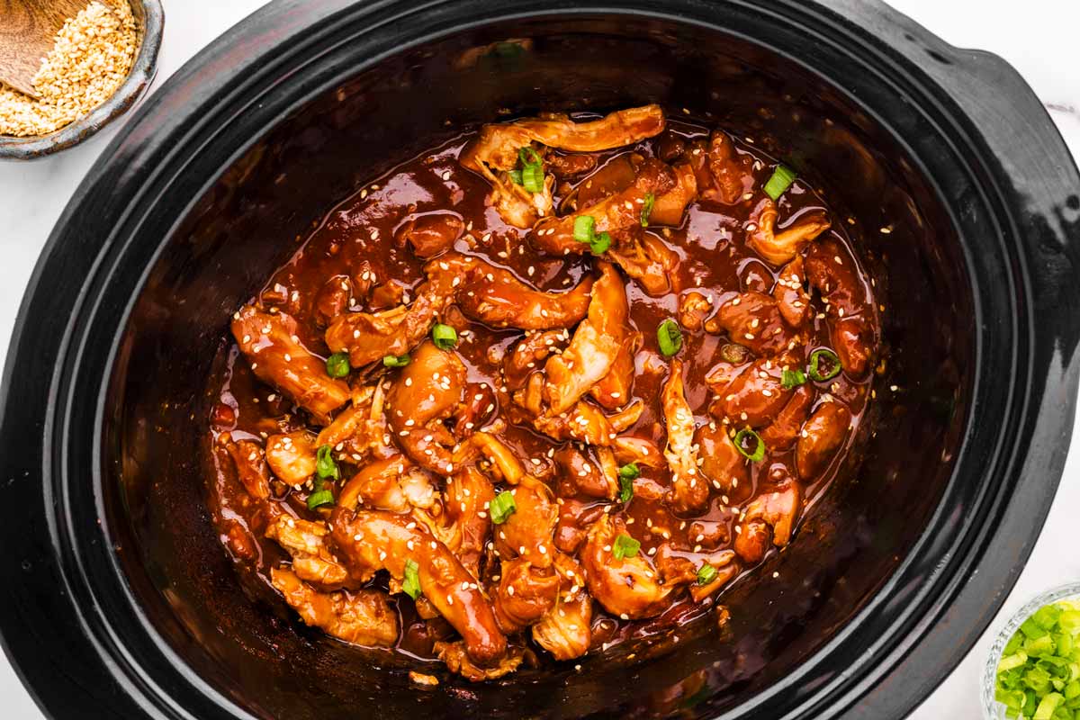 Black slow cooker crock filled with honey garlic chicken.