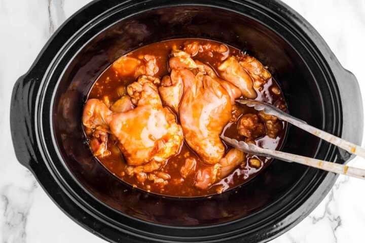 Placing chicken in slow cooker with honey garlic sauce.