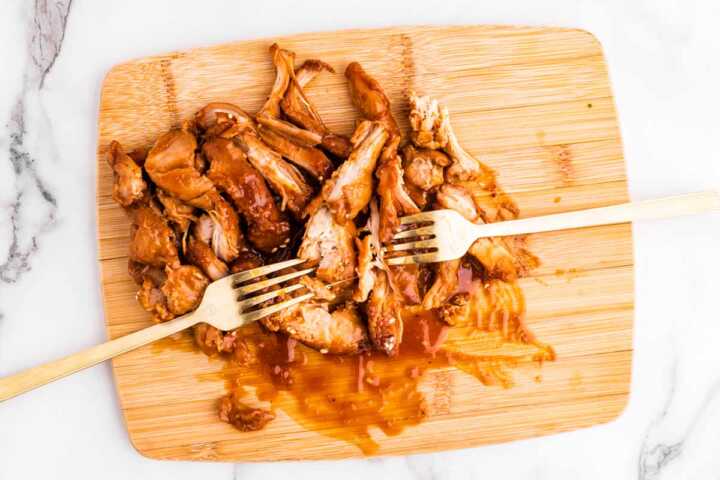 Shredding chicken on a wooden board.