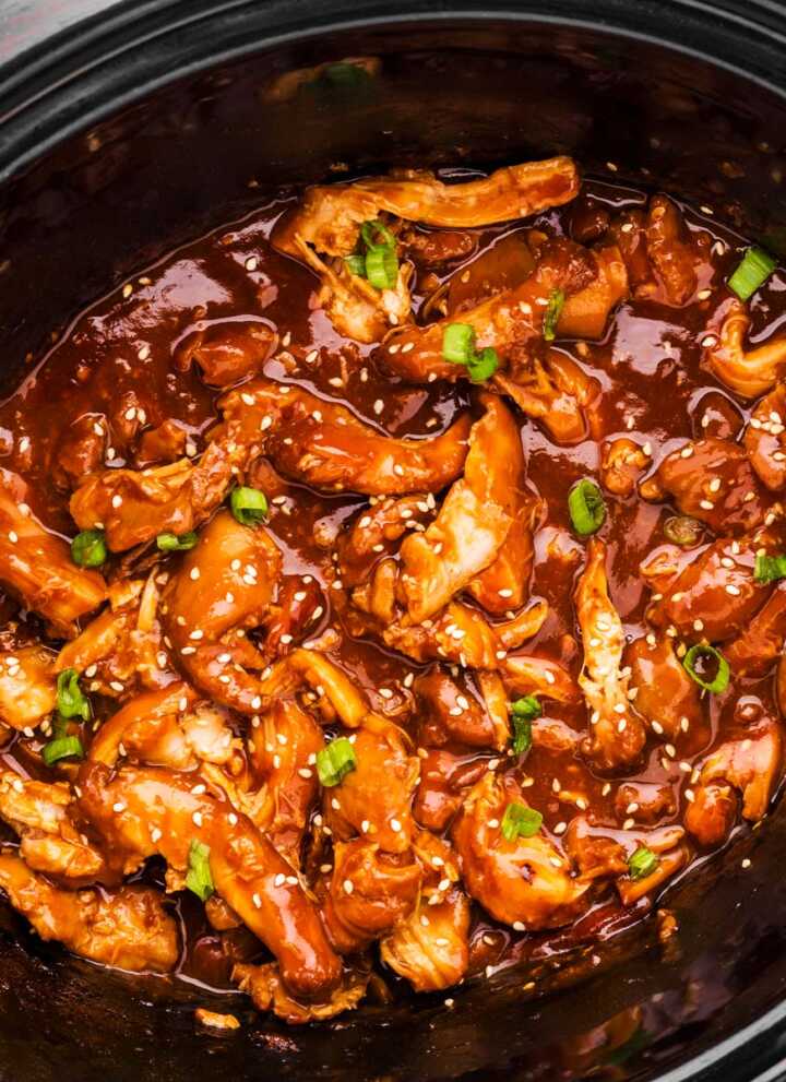 Black slow cooker crock filled with honey garlic chicken.