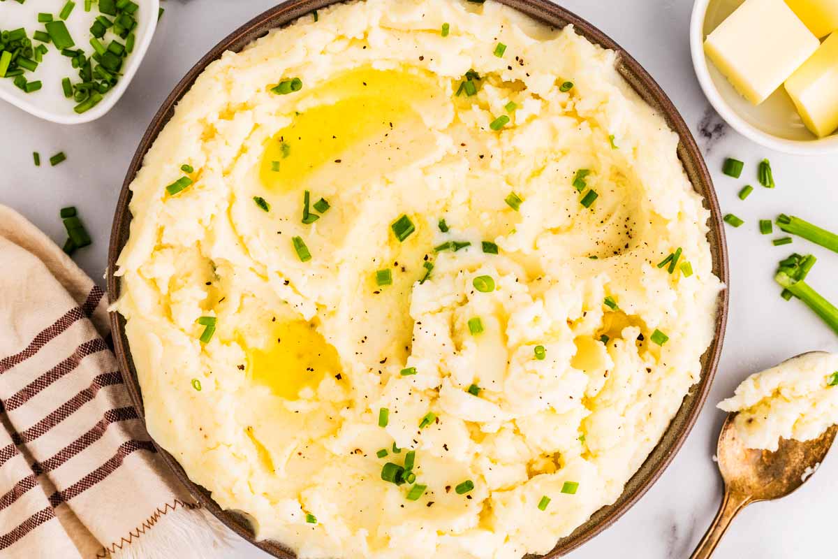 Bowl with sour cream mashed potatoes, garnished with chopped chives.