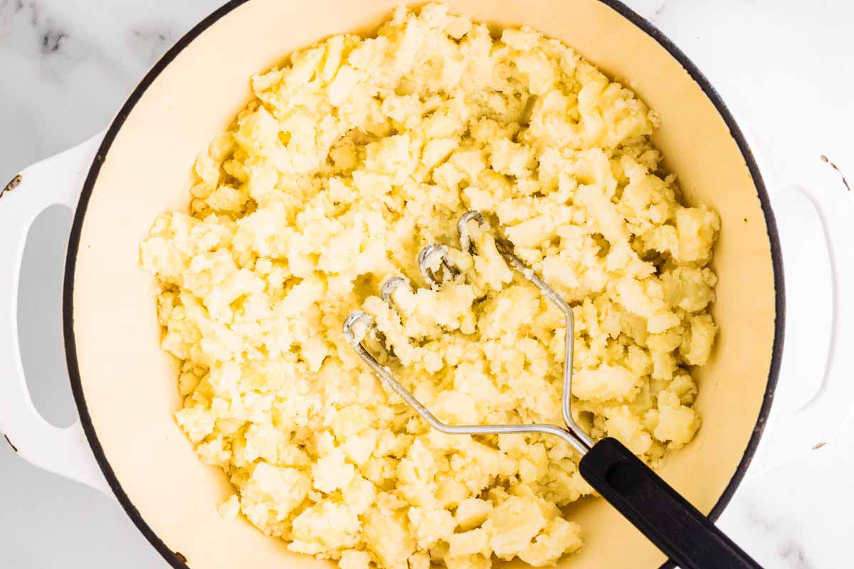 Mashing potatoes in a pot.