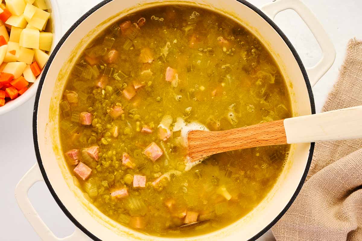 Adding ham to split pea soup.