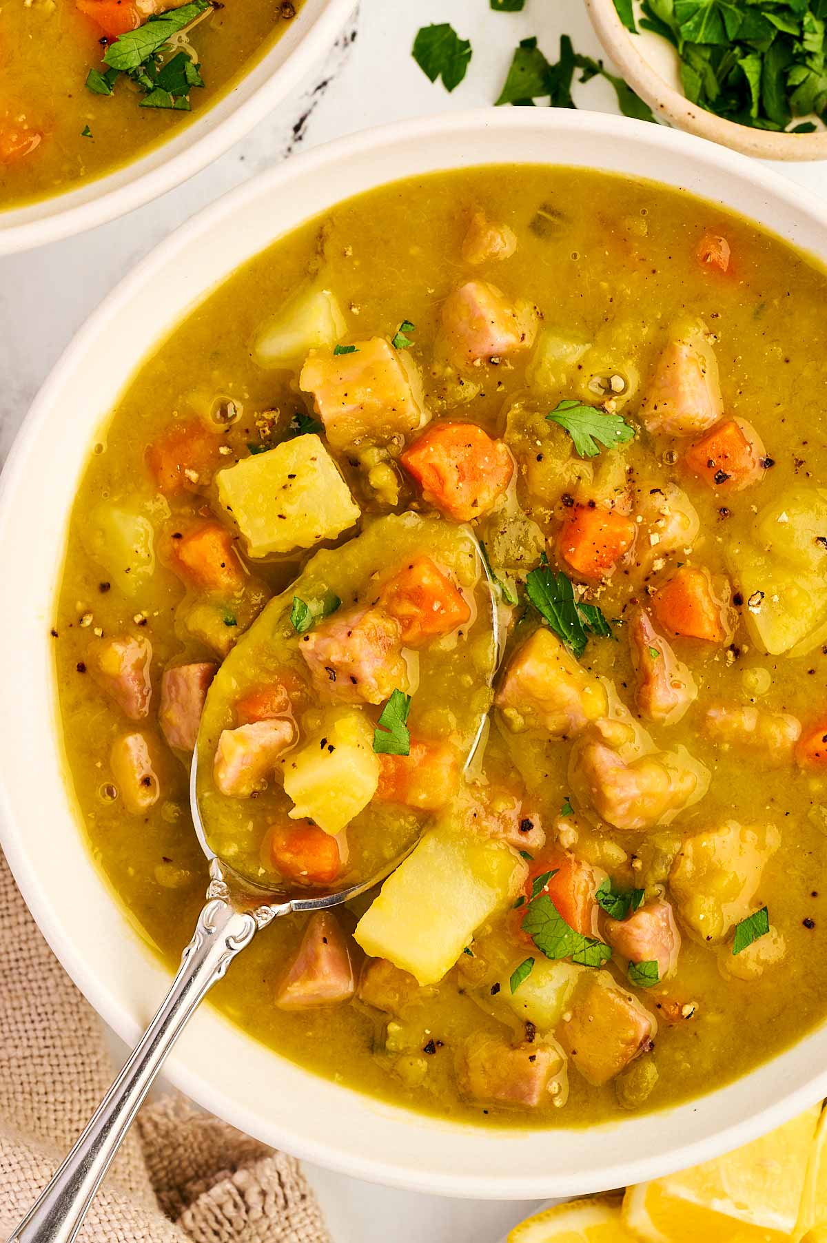 Spooning up split pea and ham soup from a bowl.