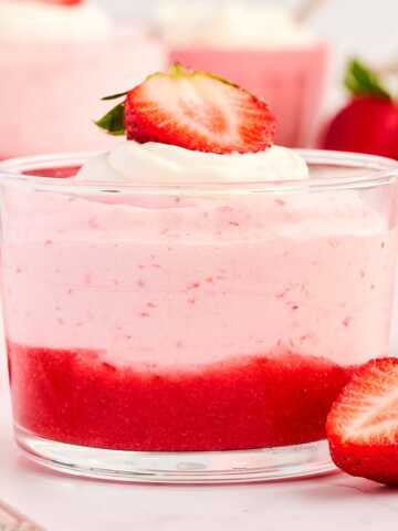 Glass cup with strawberry mousse, garnished with fresh strawberries.