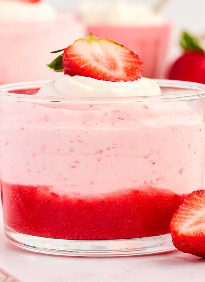 Glass cup with strawberry mousse, garnished with fresh strawberries.