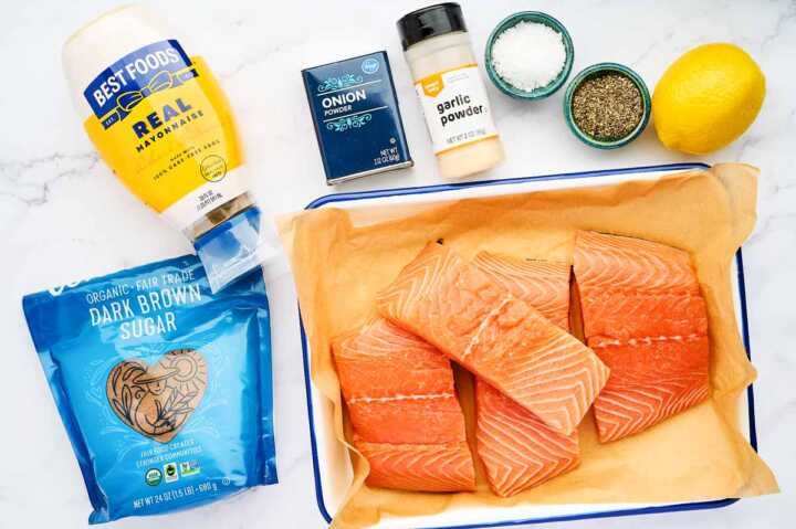 Ingredients for grilled salmon on a white marble surface.