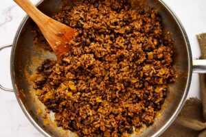 Ground beef filling with beans and green chiles in a skillet.