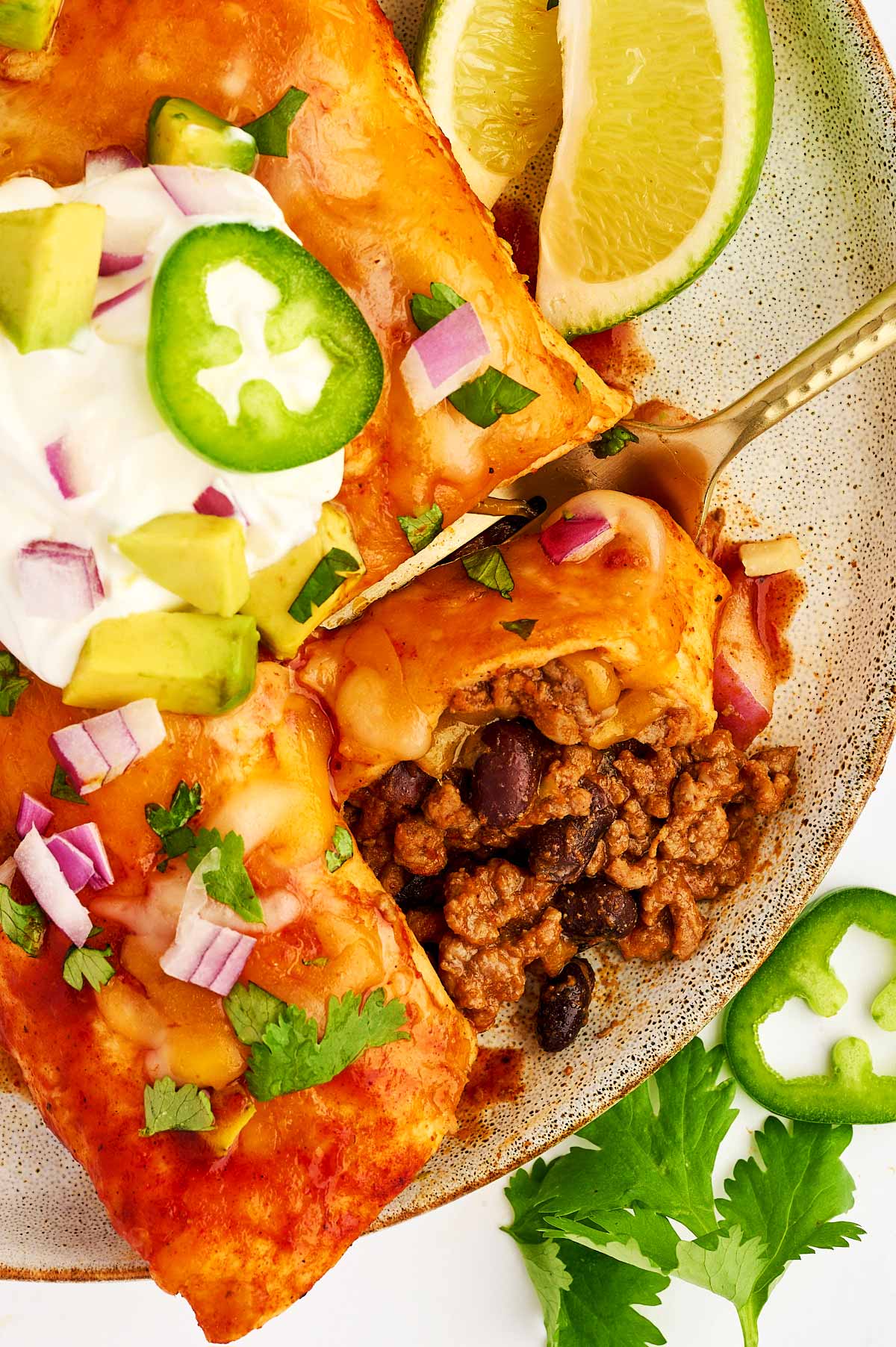 Taking a piece of ground beef enchilada with a fork.