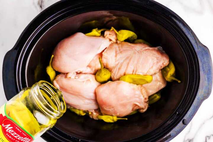 Chicken in slow cooker with peperoncini peppers.