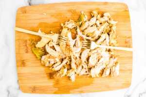 Shredding chicken on a wooden board.