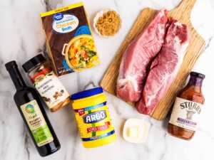 Overhead view of the groceries for slow cooker pork tenderloin on a white marble surface.