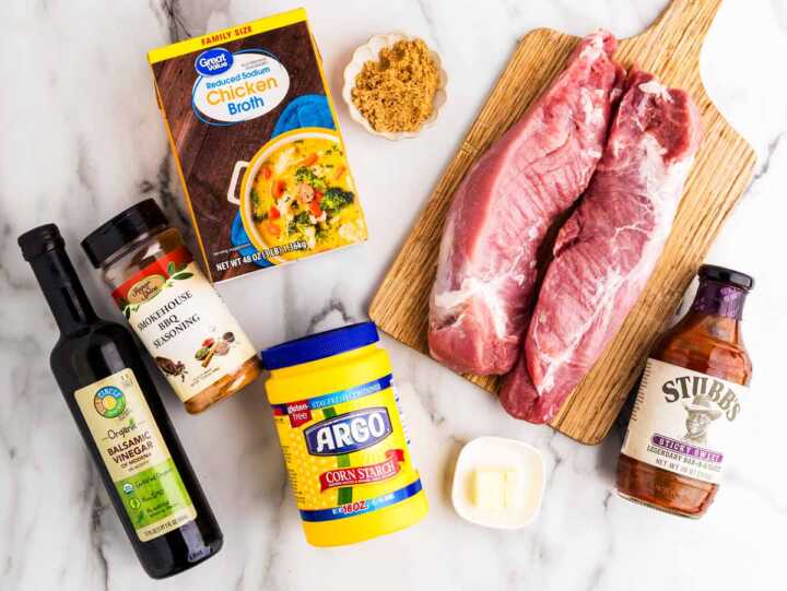 Overhead view of the groceries for slow cooker pork tenderloin on a white marble surface.