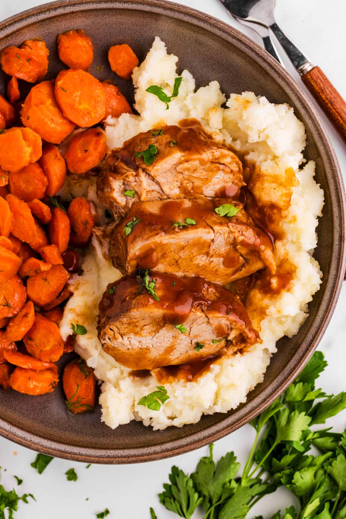Overhead view of plate loaded with mashed potatoes, sliced carrots and pork tenderloin.