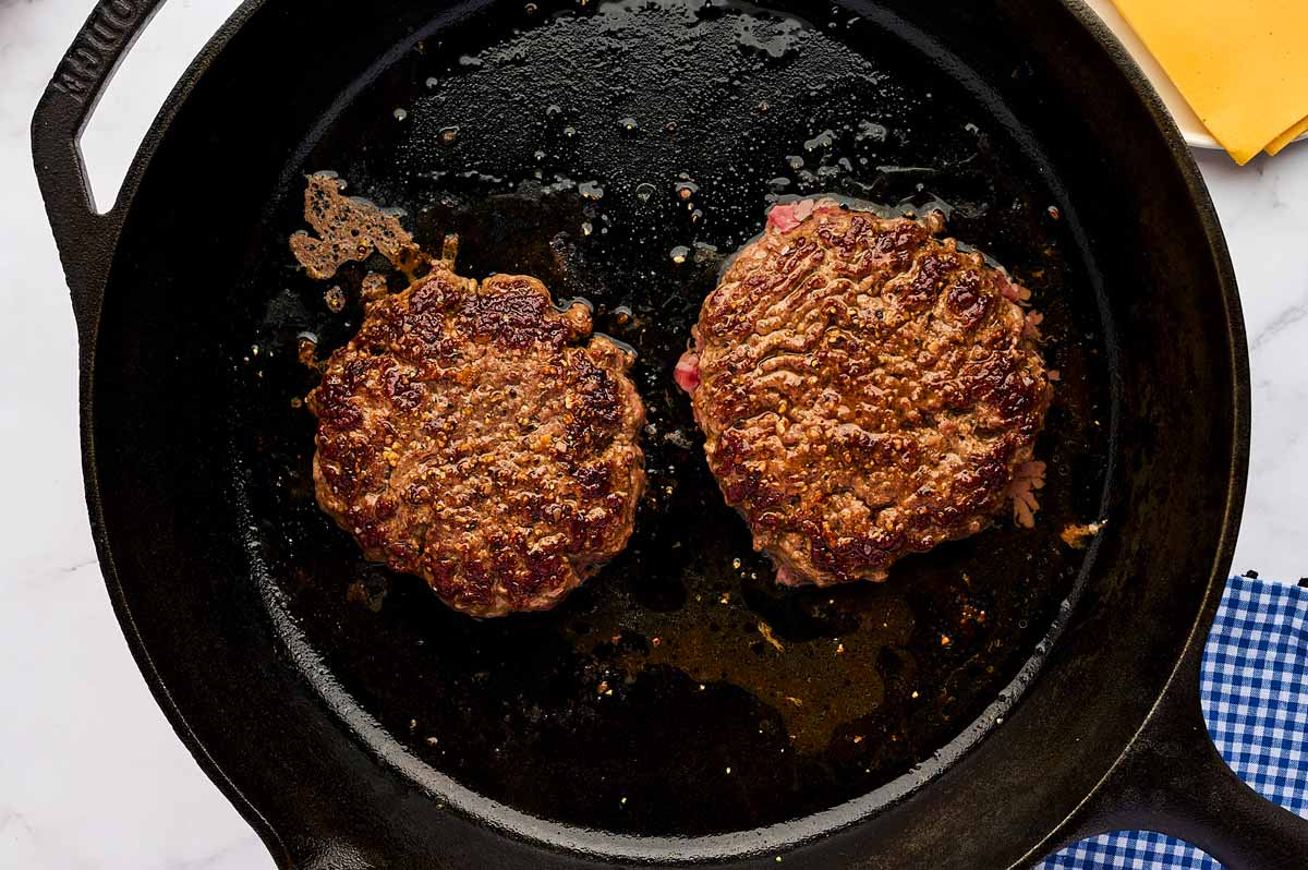 Two burger patties in a skillet.