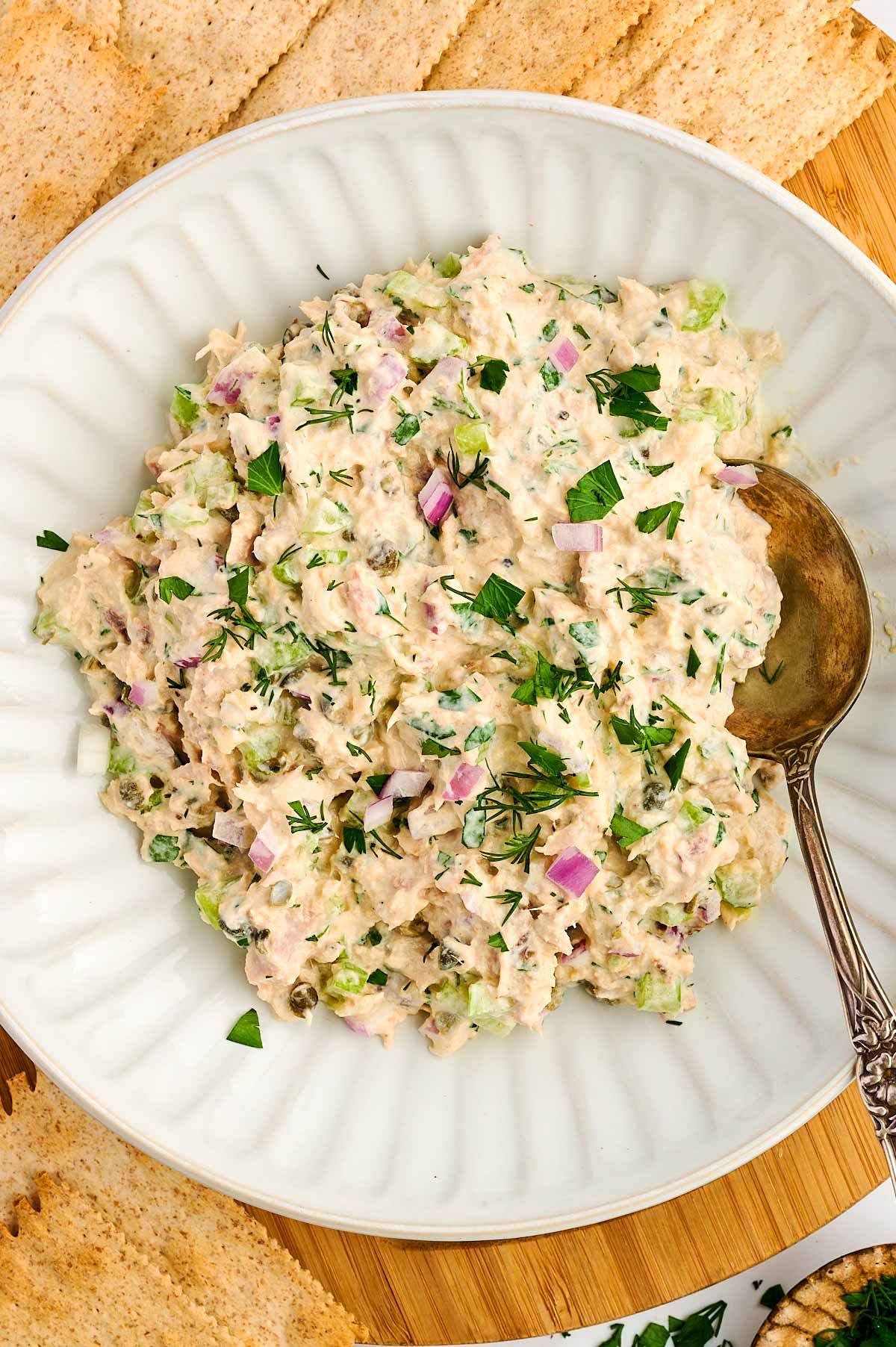 Bowl of tuna salad surrounded by crackers.
