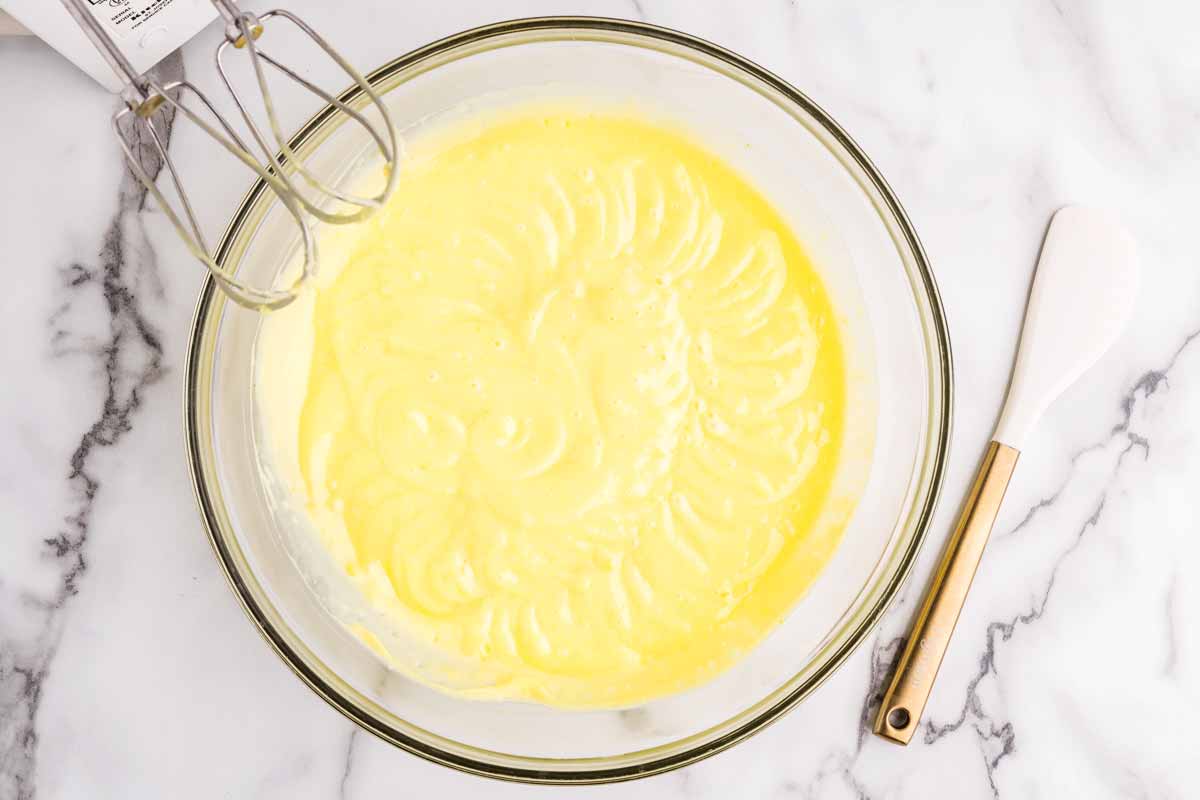 Whisking yellow lemon pudding in a large bowl
