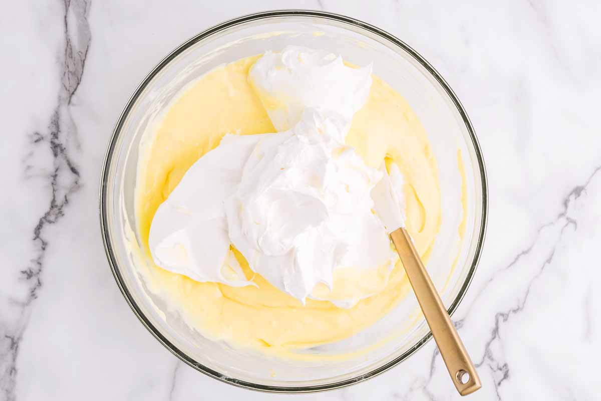 Folding white whipped topping into the lemon cream mixture.