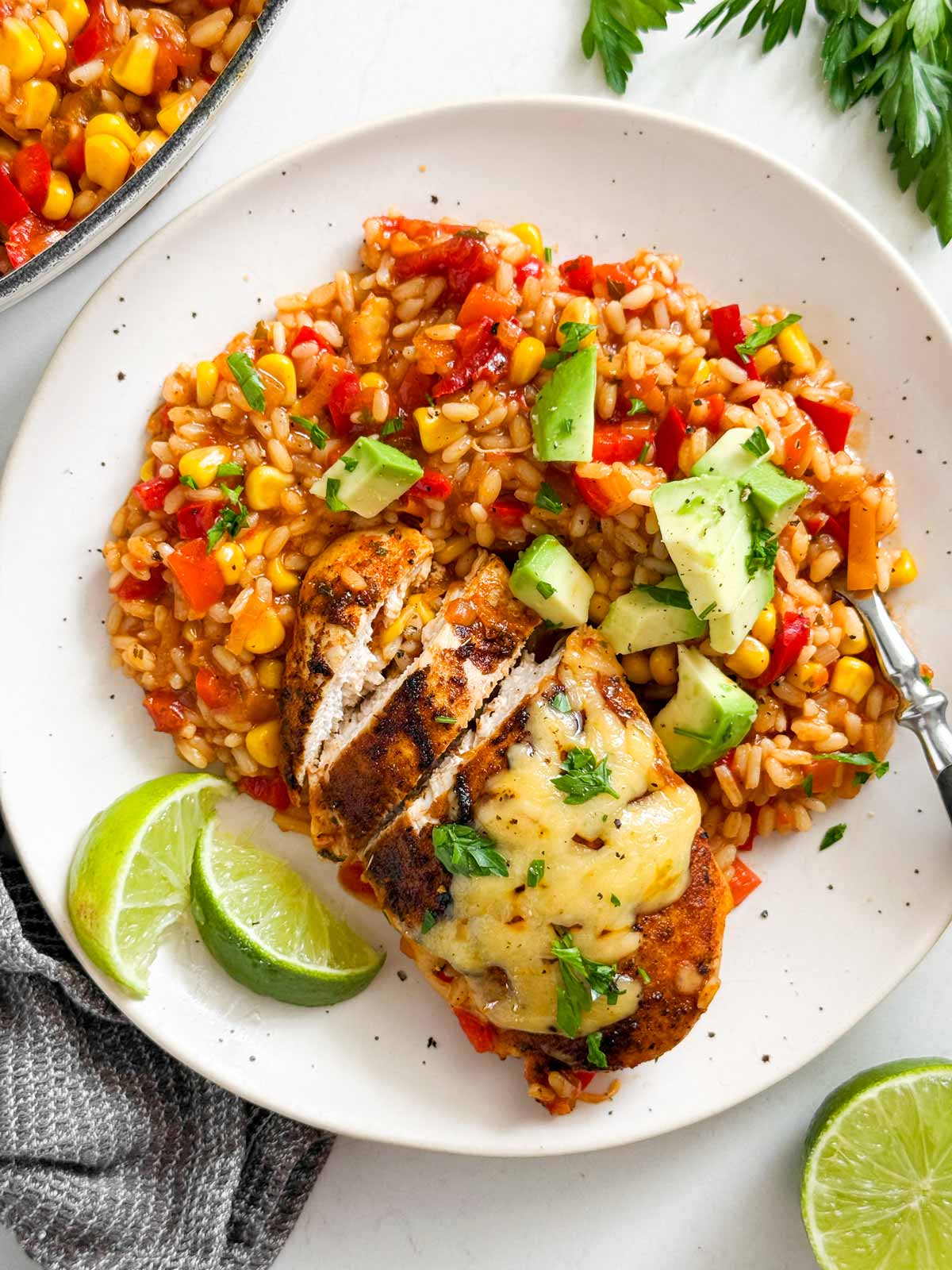 Plated salsa chicken and rice with avocado, lime slices and cilantro.