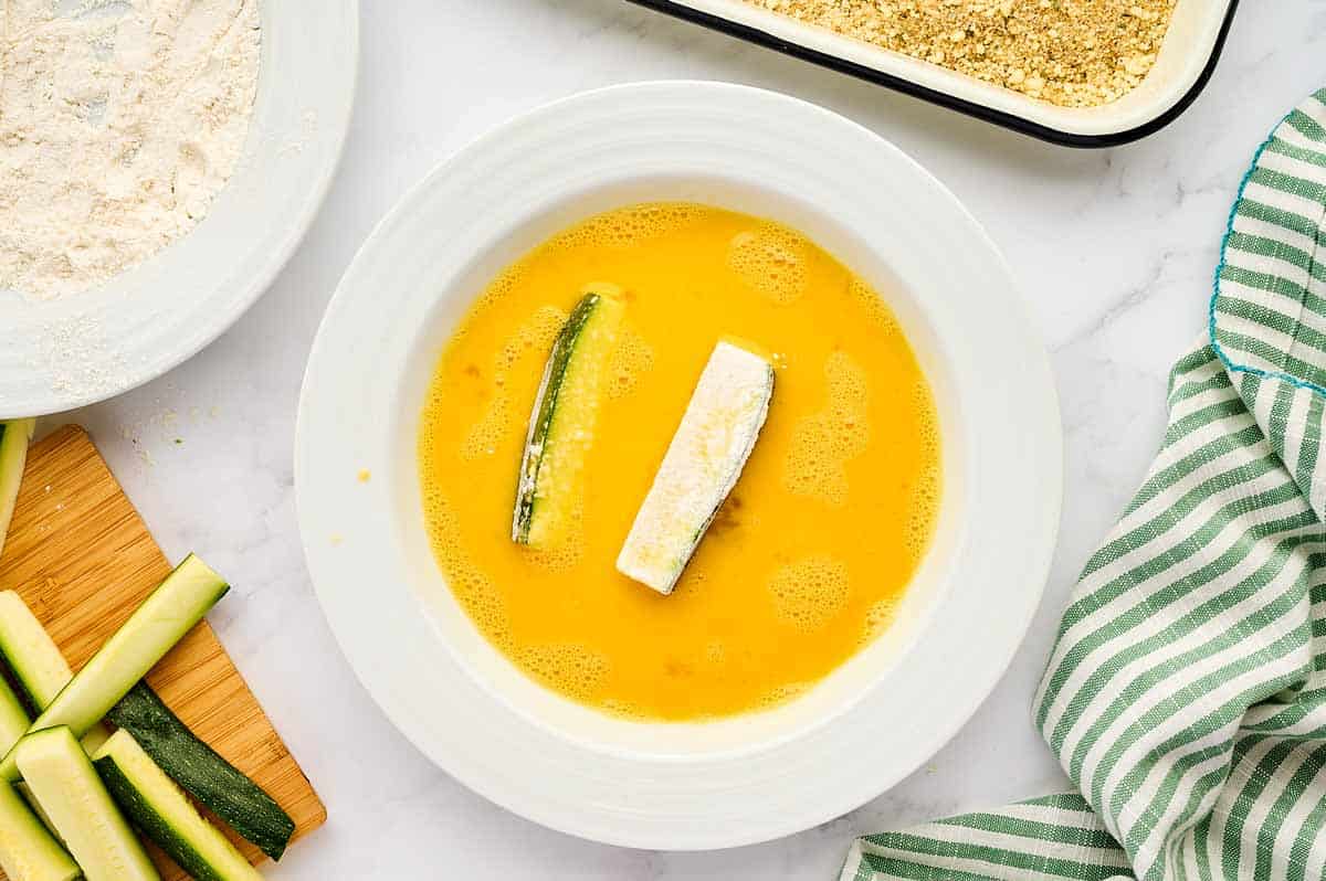 Zucchini fries in egg wash.
