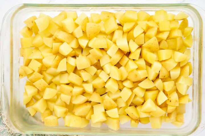 Cooling diced and cooked potatoes in a shallow dish.