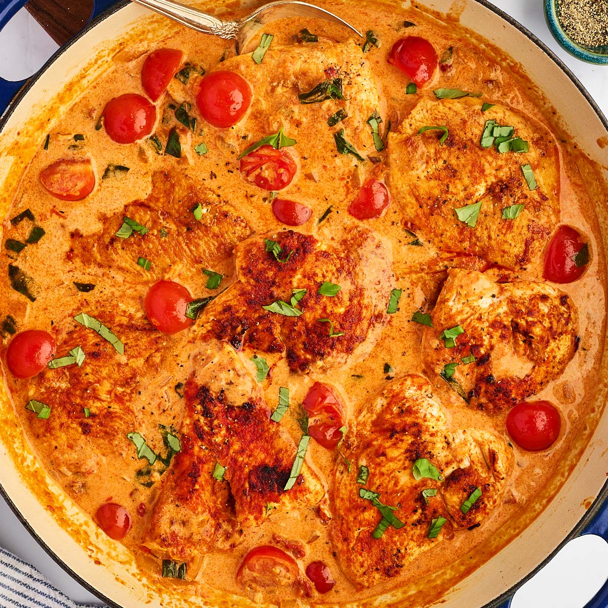 Overhead view of a skillet filled with creamy tomato basil chicken.