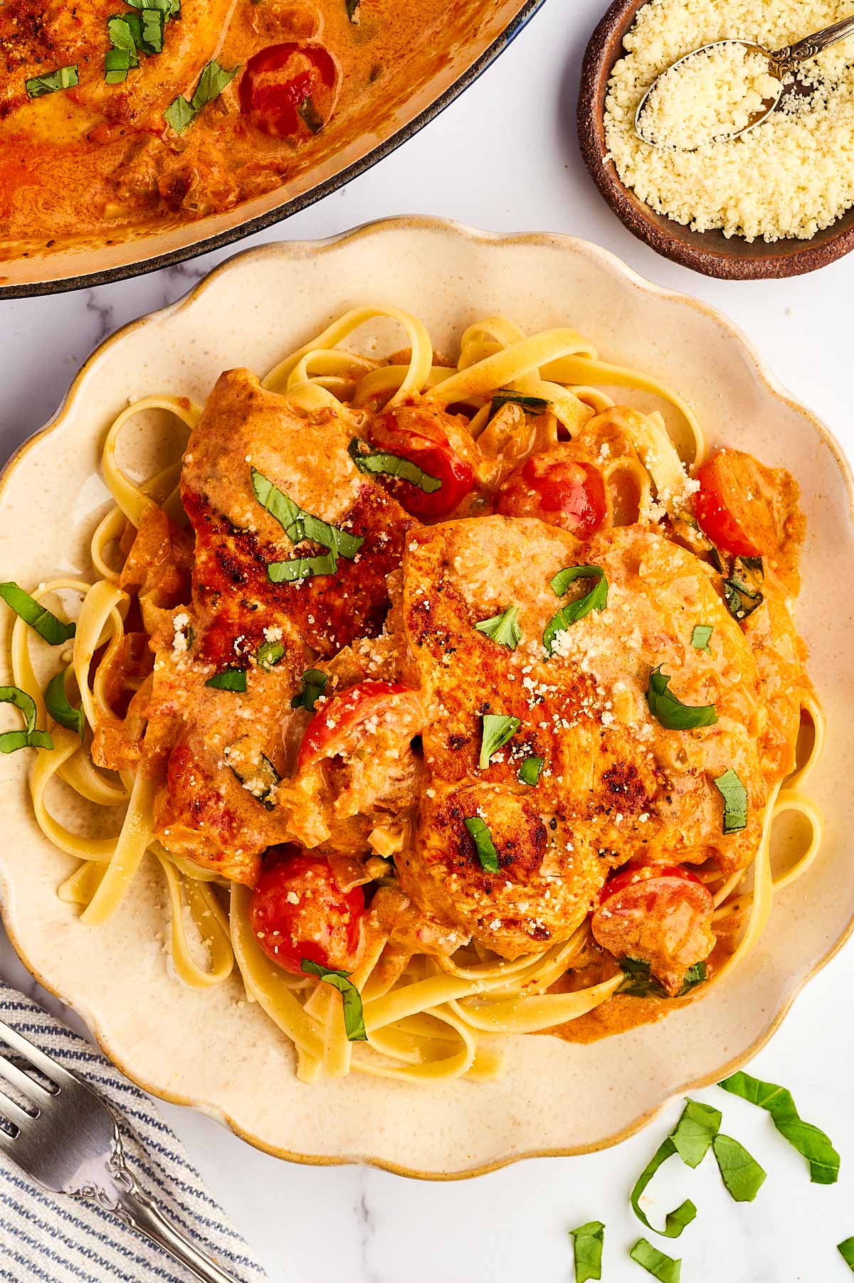 Tomato basil chicken on a plate over pasta.