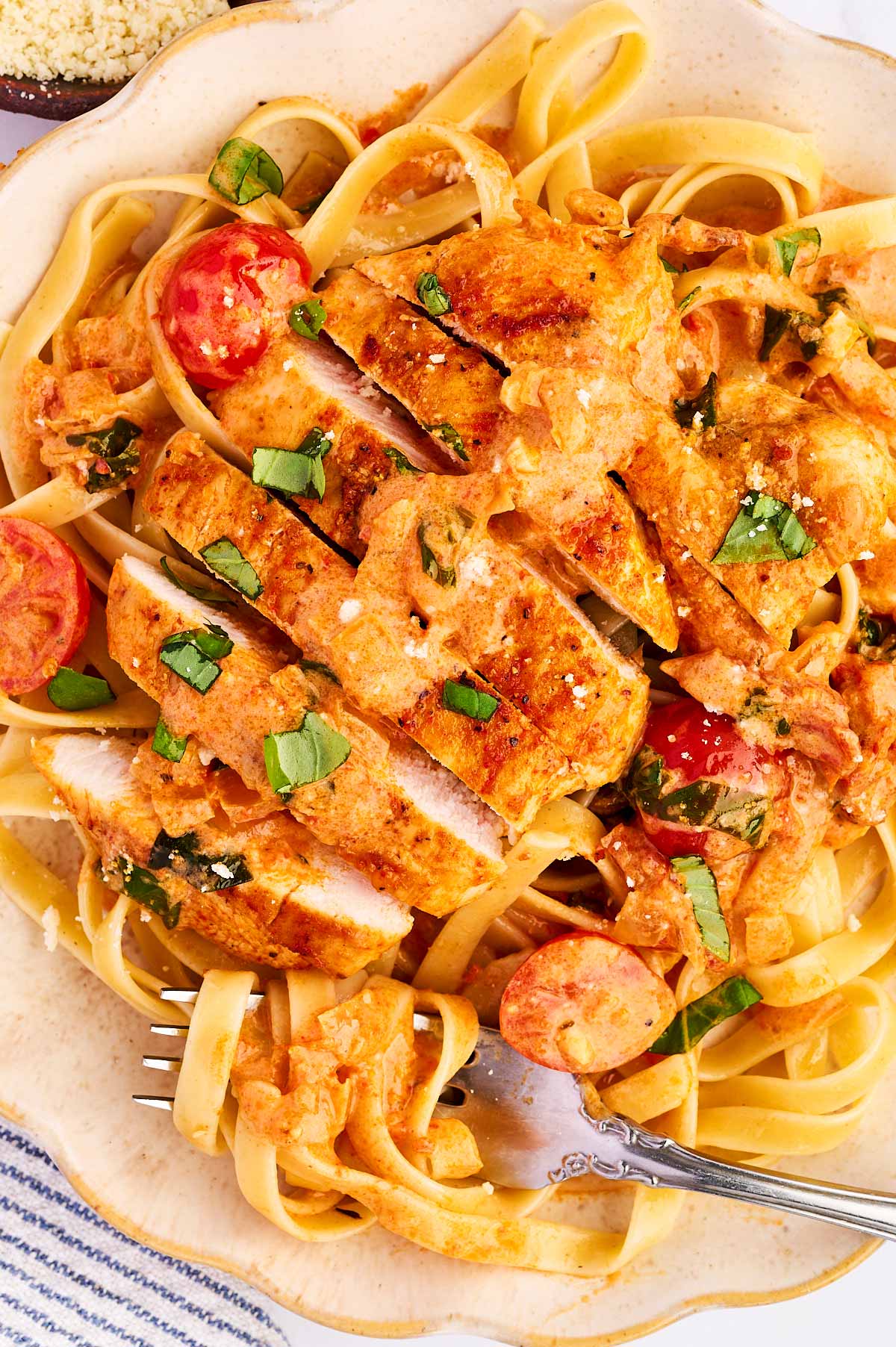 Sliced chicken in tomato basil sauce over pasta.