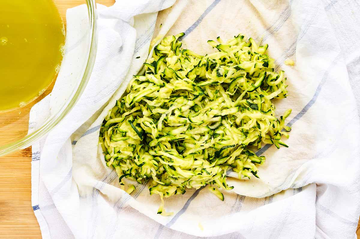 Squeezing shredded zucchini with a tea towel.