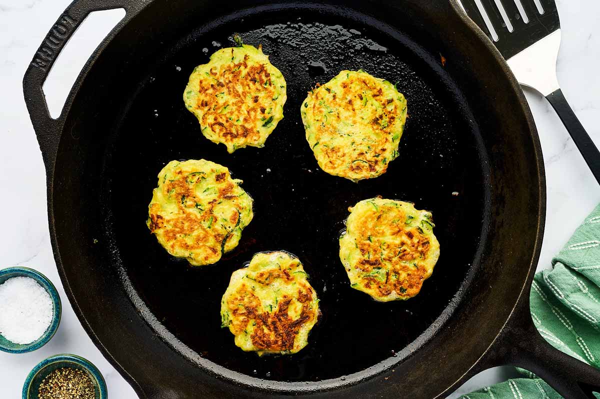 Cooked zucchini fritters in a skillet.