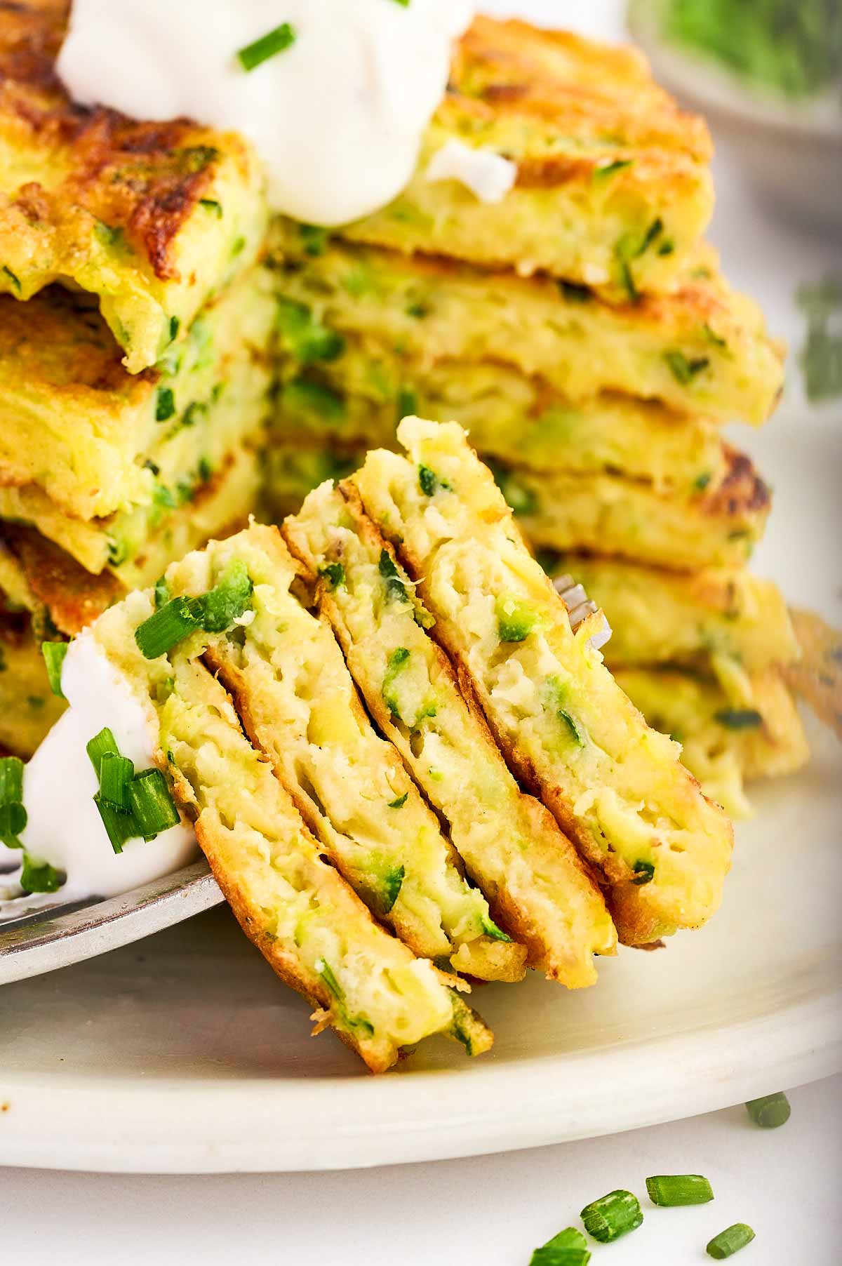 Wedge of zucchini fritters stacked on a fork.