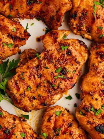 Platter with grilled chicken thighs and parsley.