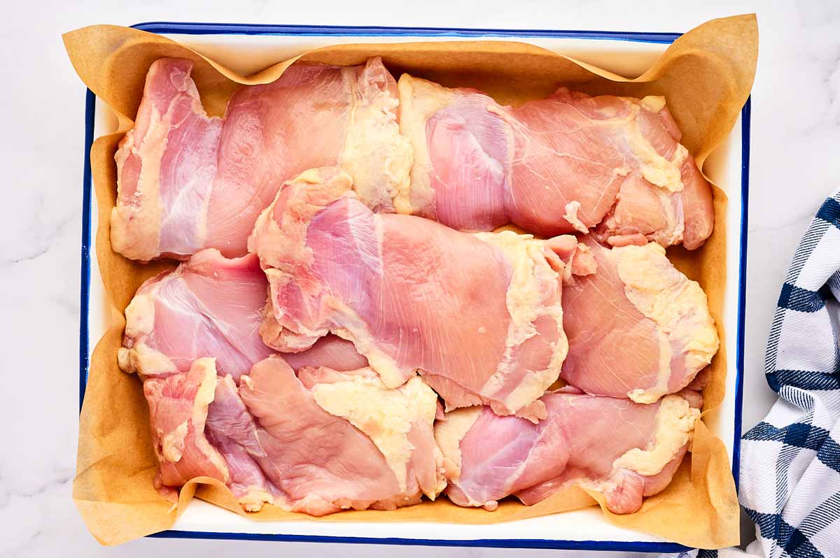 flattened out chicken thighs in a pan.