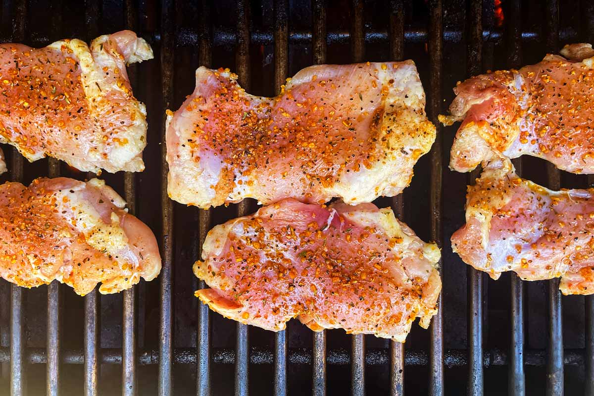 Chicken thighs on grill grates.