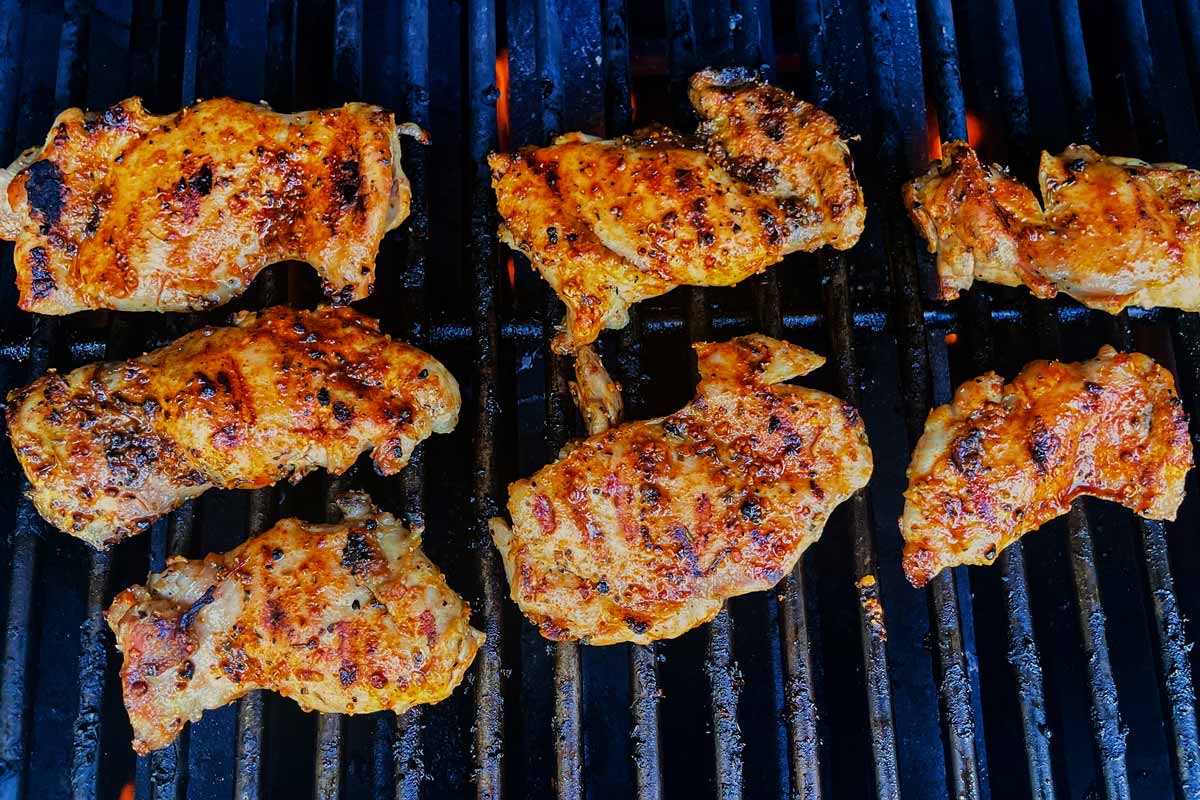 Fully grilled chicken thighs on grill grates.