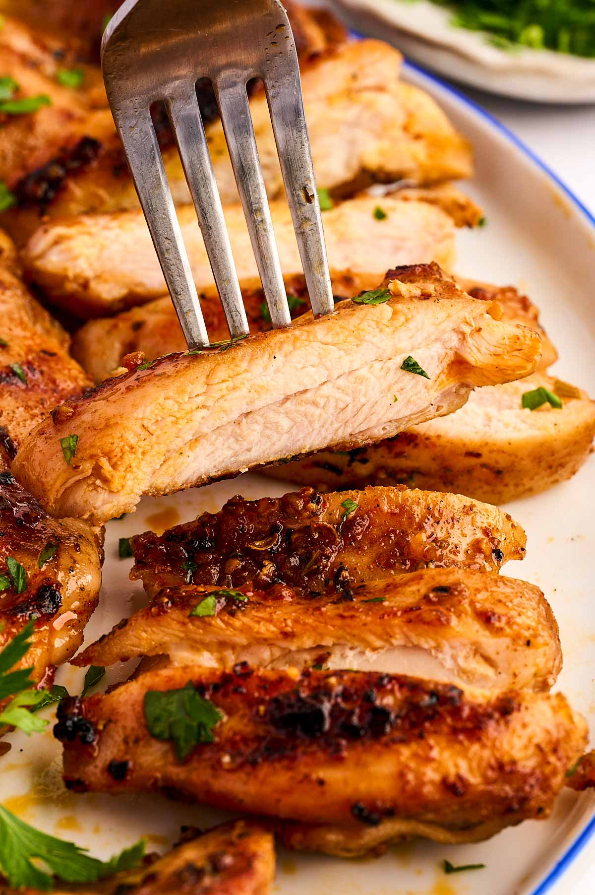 Slice of grilled chicken thigh on a fork.