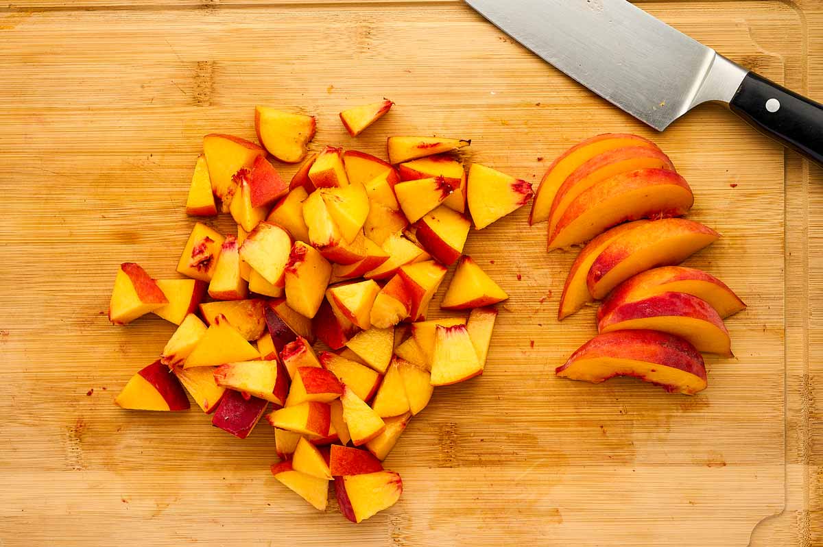 Sliced and diced peaches on a wooden cutting board.