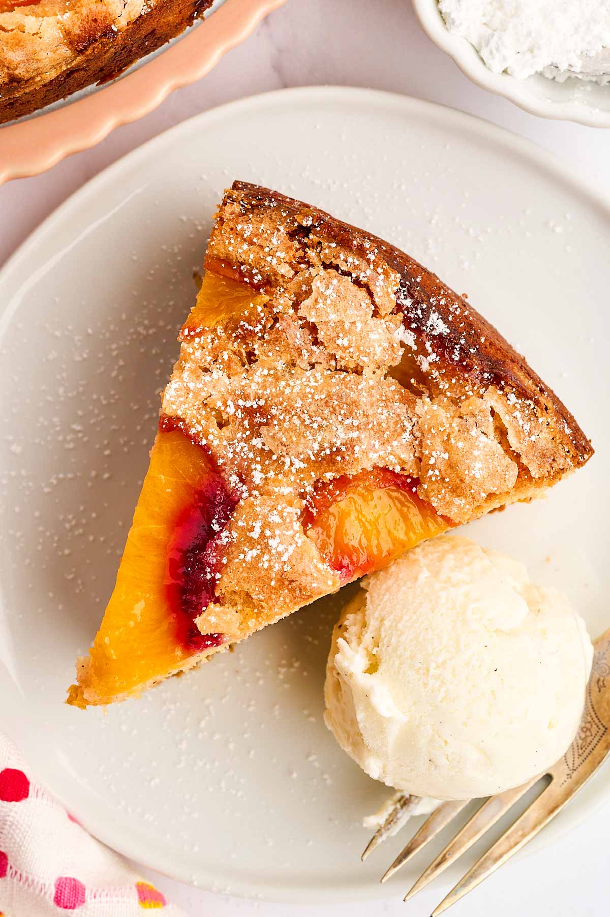 Overhead view of a slice of peach cake with a scoop of vanilla ice cream.