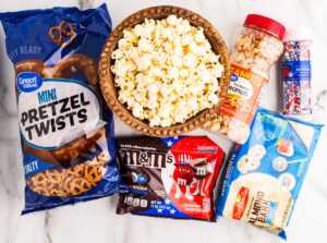 Ingredients to make Red, White and Blue popcorn on a white marble surface.