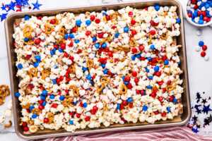 Patriotic popcorn on a sheet pan with red, white and blue decorations around.