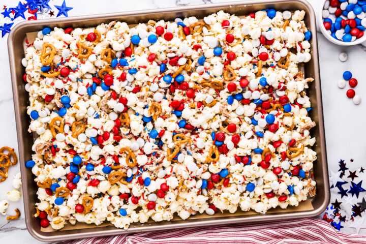 Patriotic popcorn on a sheet pan with red, white and blue decorations around.