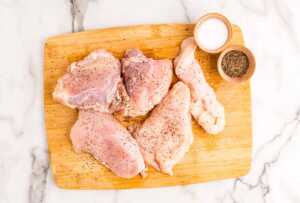 Seasoned chicken pieces on a wooden board.