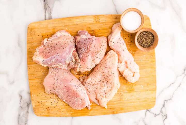Seasoned chicken pieces on a wooden board.