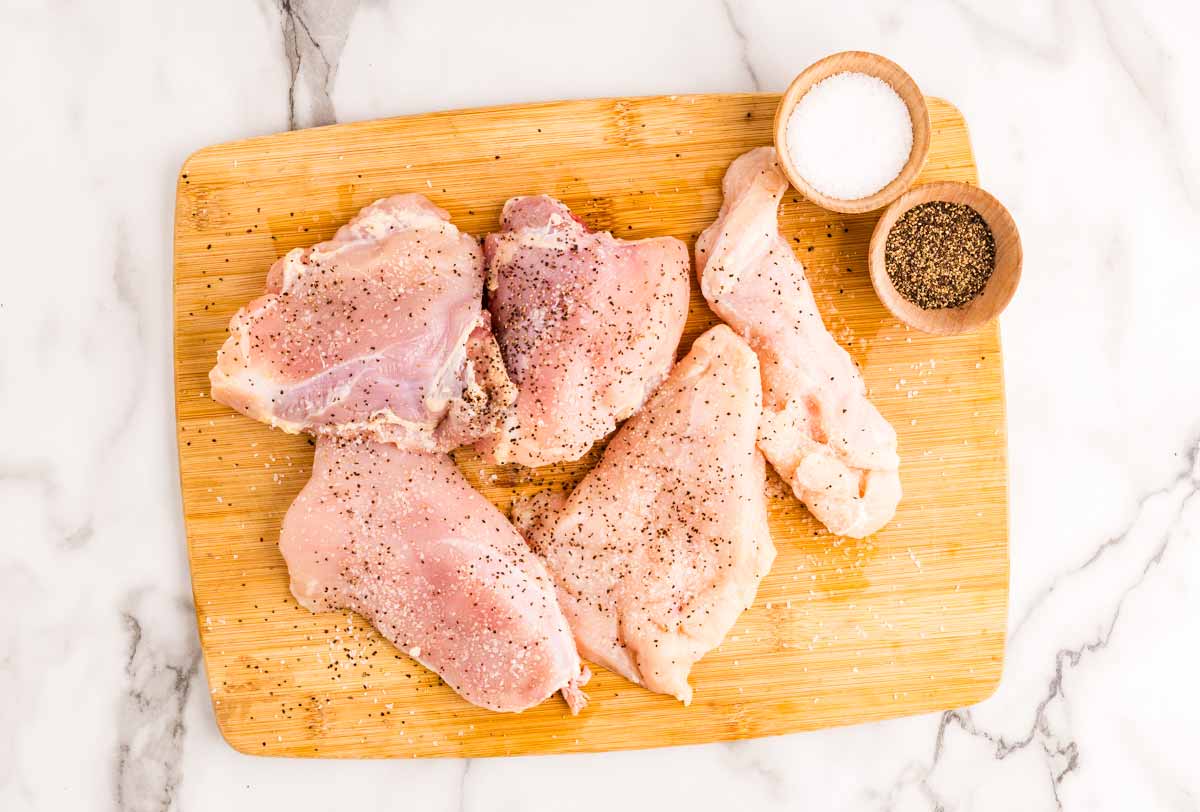 Seasoned chicken pieces on a wooden board.
