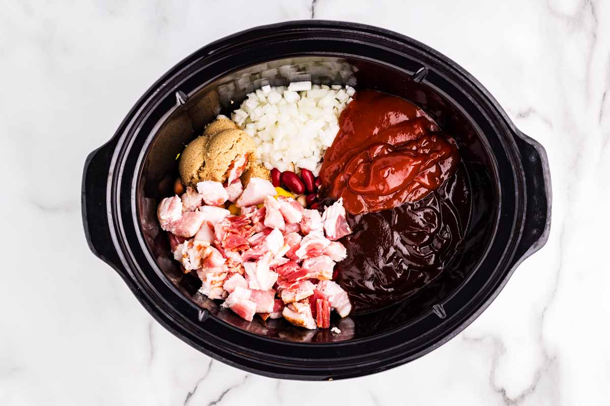 Ingredients to make baked beans in a slow cooker crockery insert.
