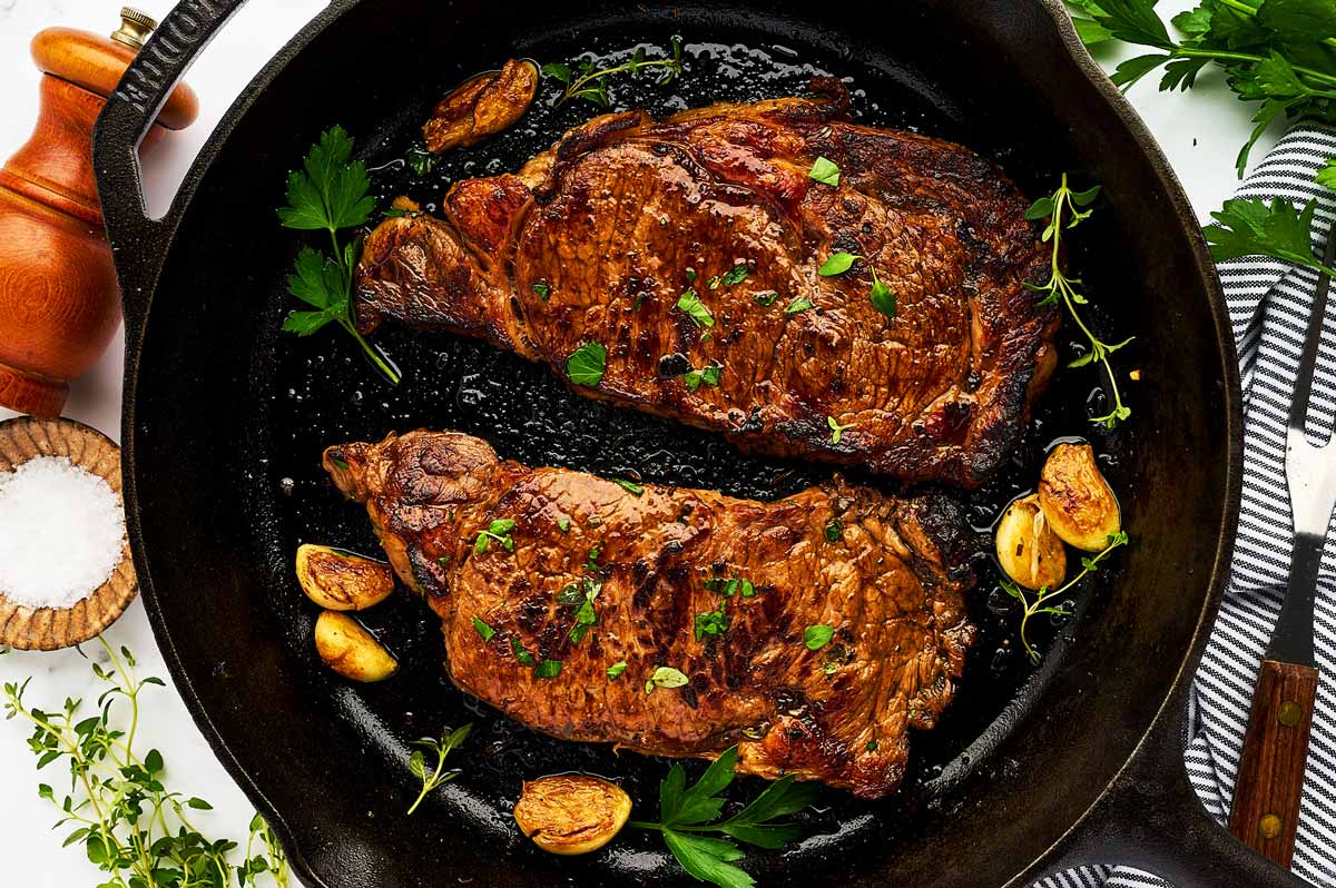 Marinated cooked steaks in a cast iron skillet.