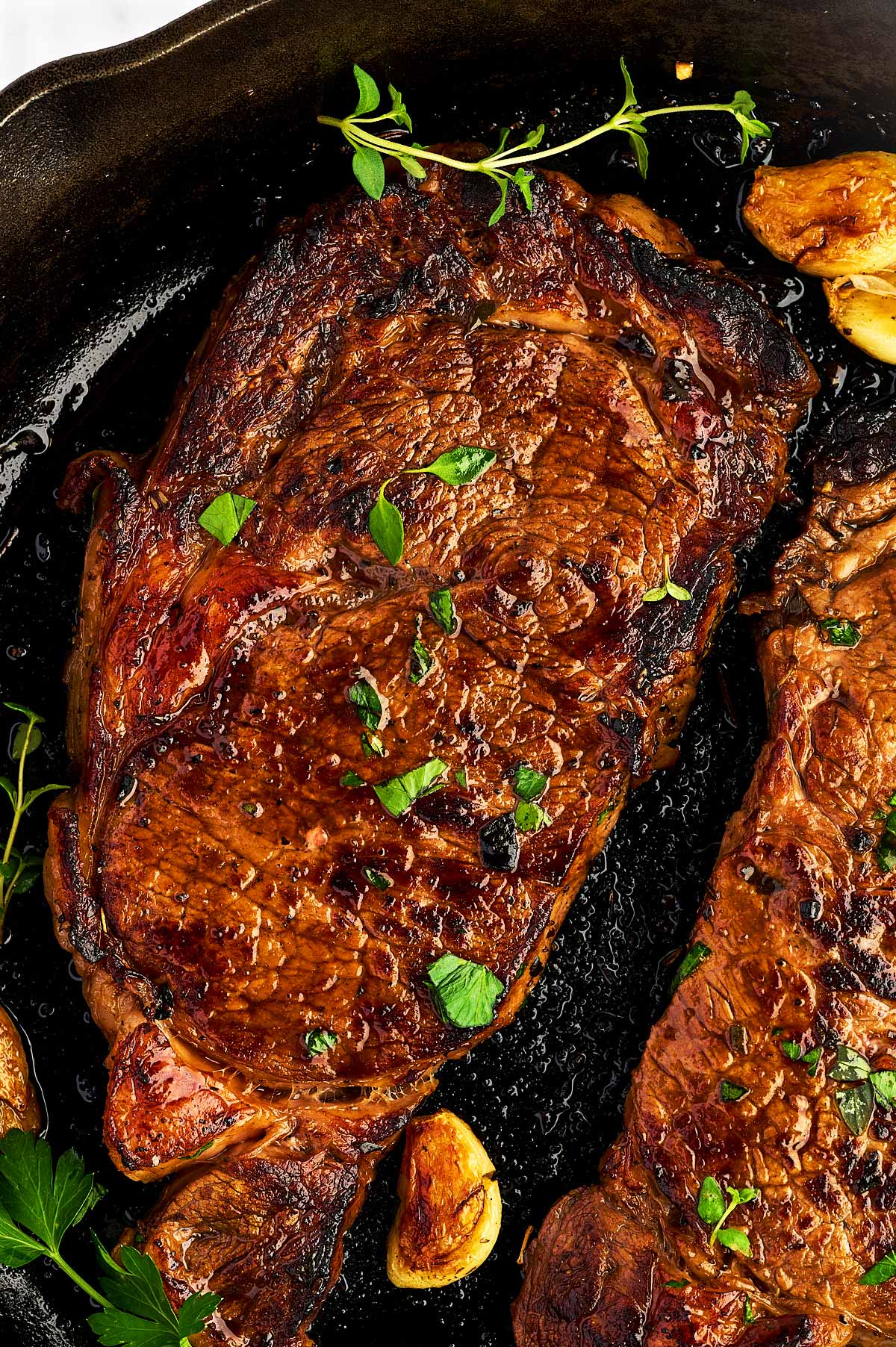 Close up of a cooke marinated steak in a cast iron skillet.