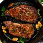 Marinated cooked steaks in a cast iron skillet.